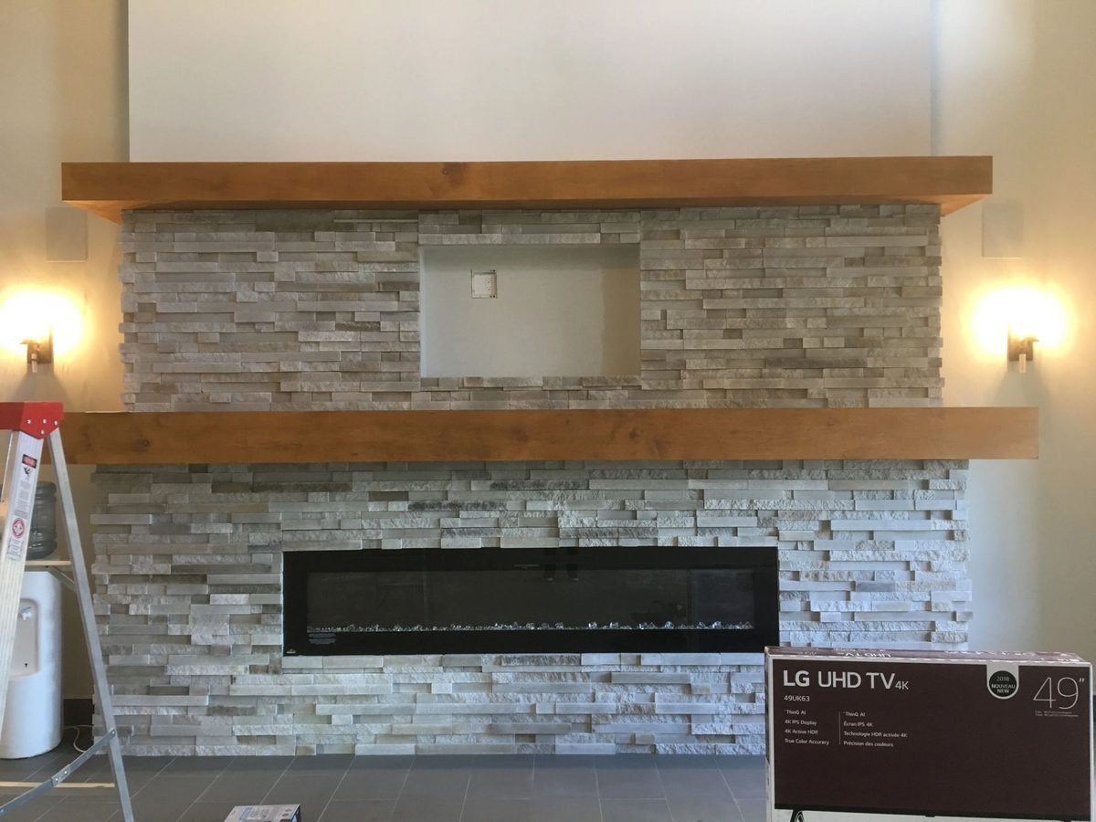 TV recessed into a stacked stone wall between wall sconces
