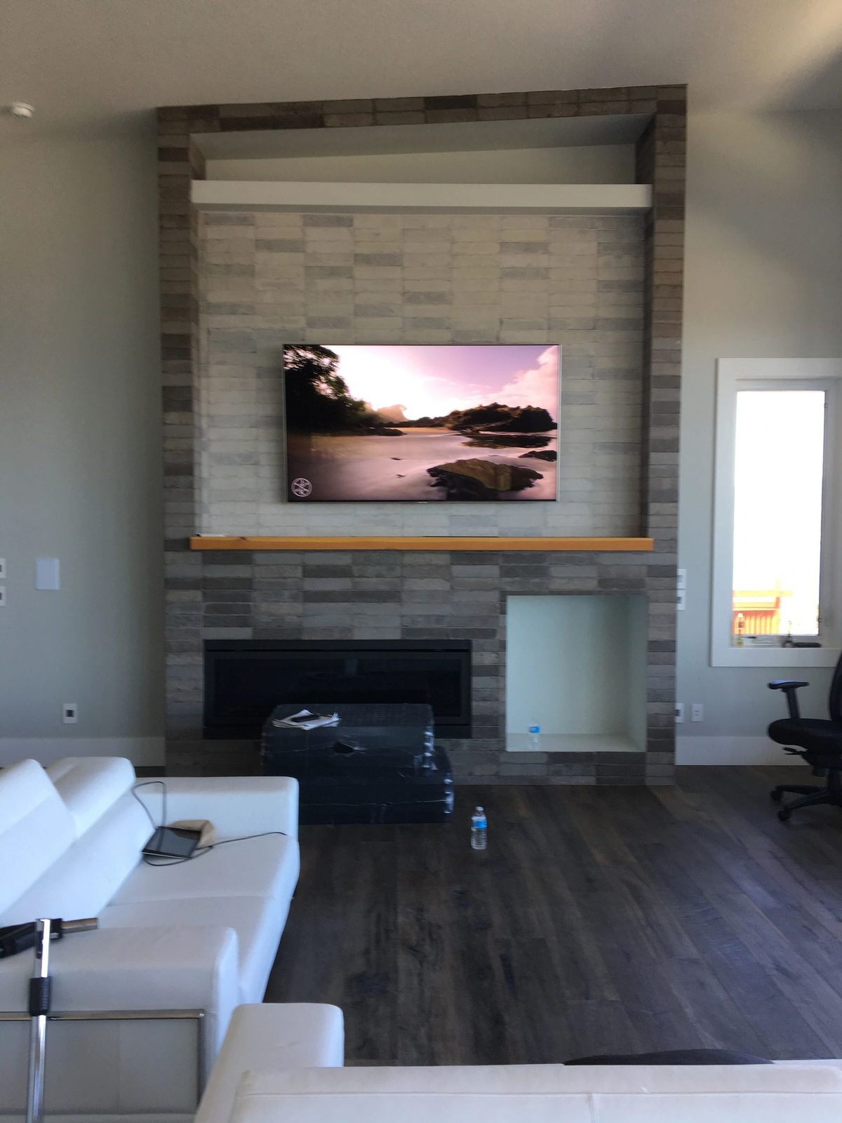 TV mounted on a stacked stone fireplace wall with timber mantle