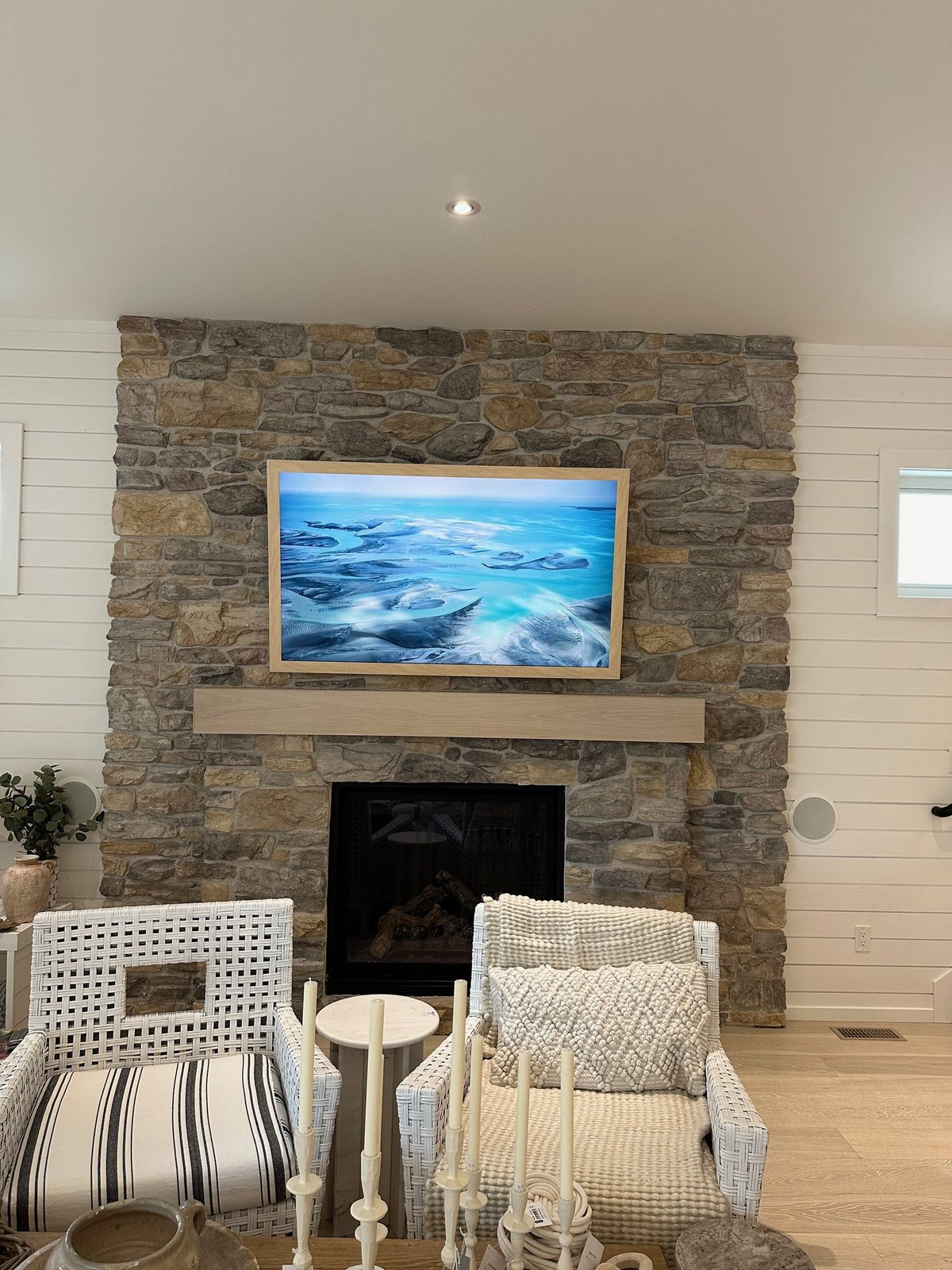Frame TV on a fieldstone chimney with a white oak mantel and shiplap walls