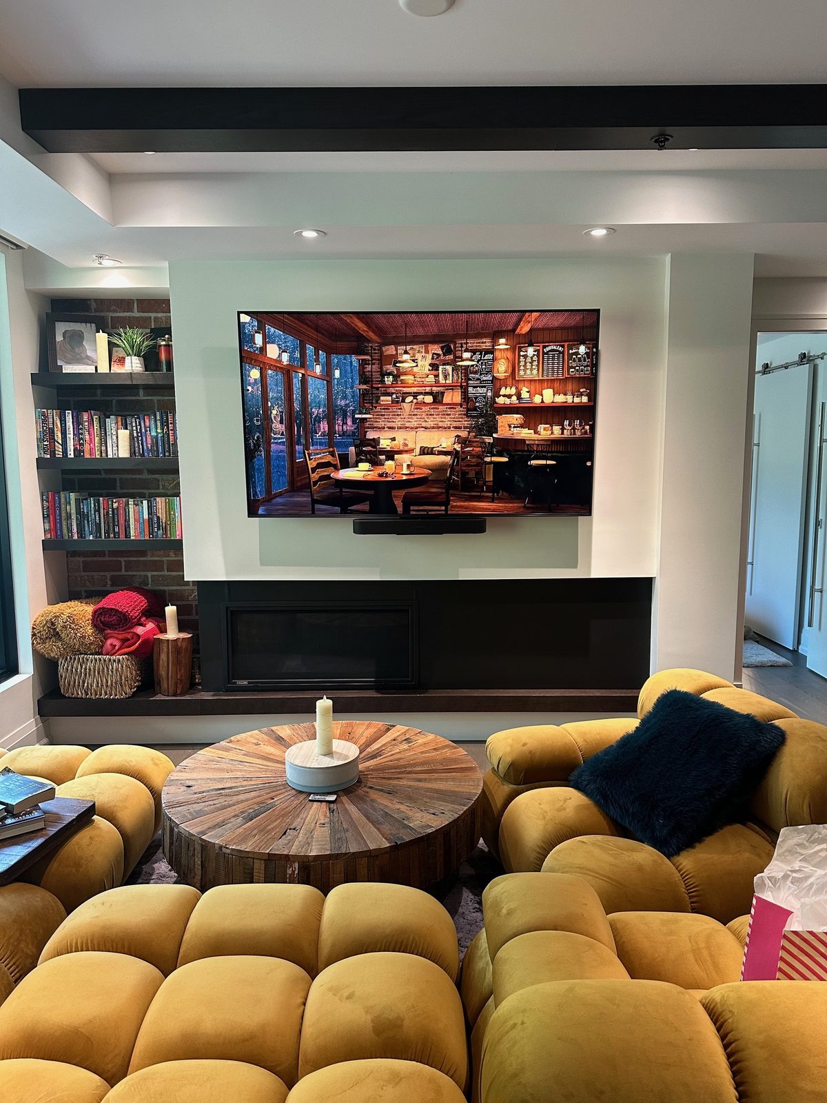 TV mounted on a recessed panel above a linear fireplace with brick bookshelves