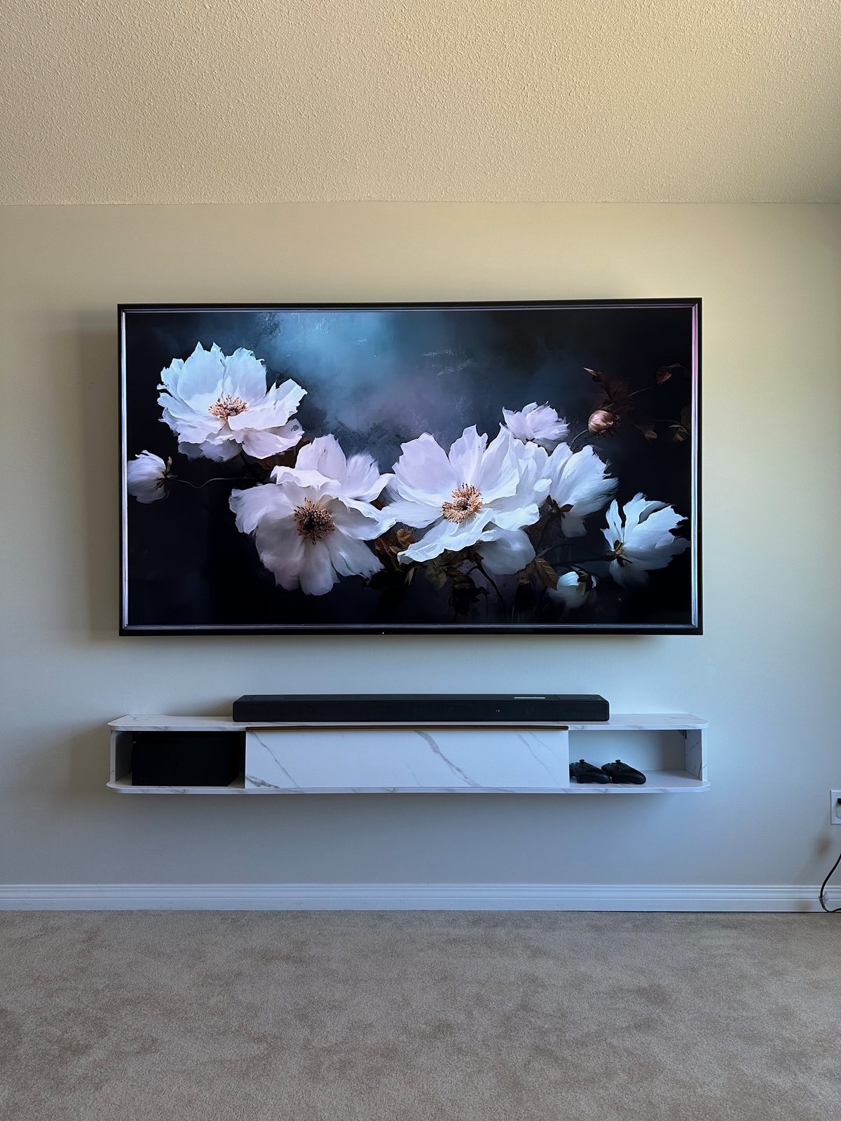 Frame TV in art mode above a floating marble console with a mounted soundbar