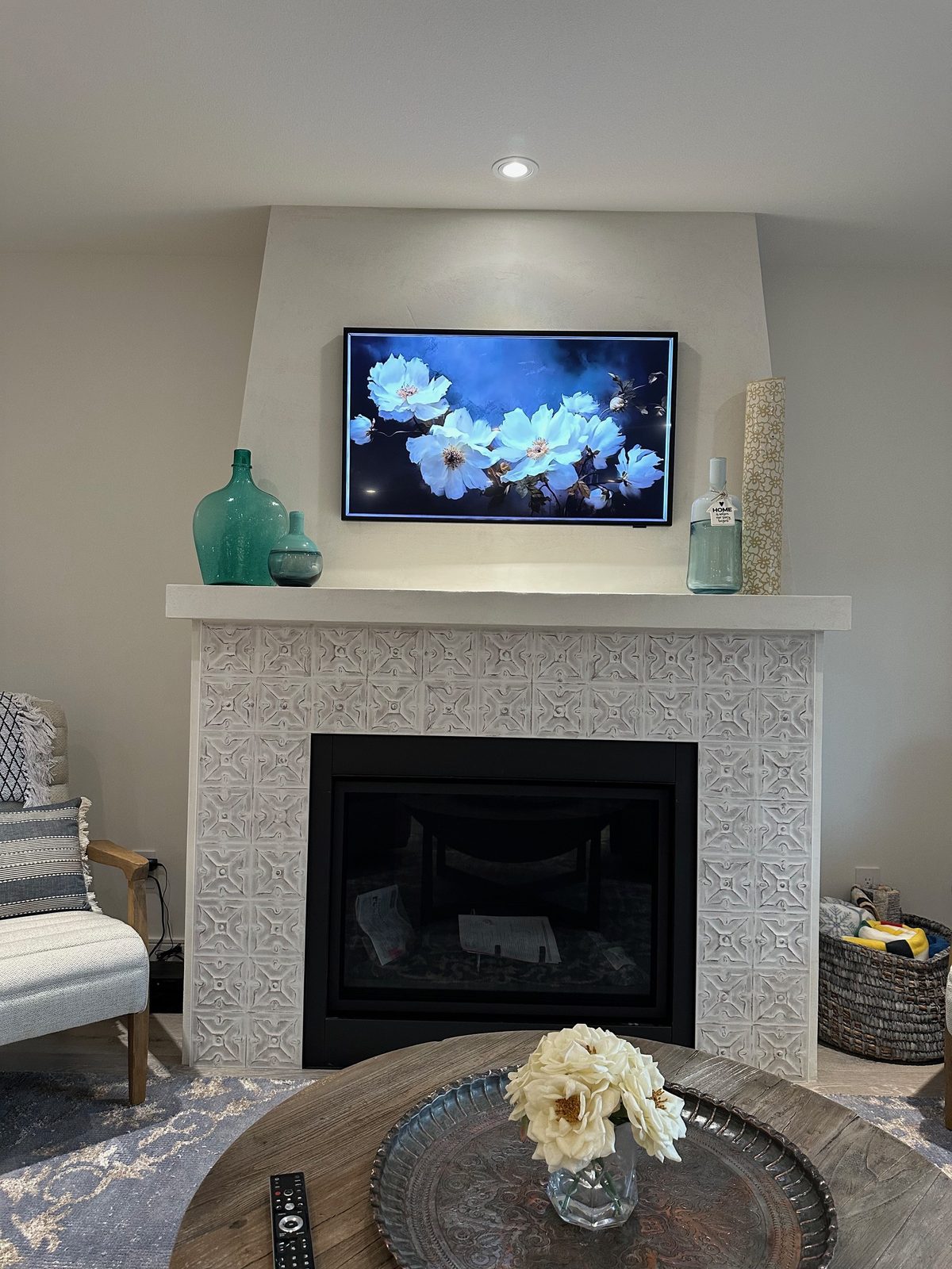 TV mounted flush on a plaster chimney breast above a tiled fireplace