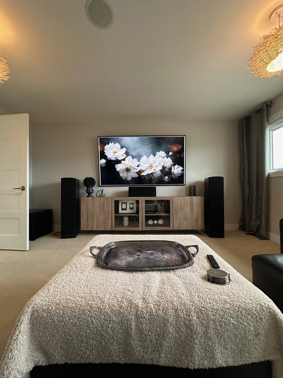 Large TV between floorstanding tower speakers above a floating credenza