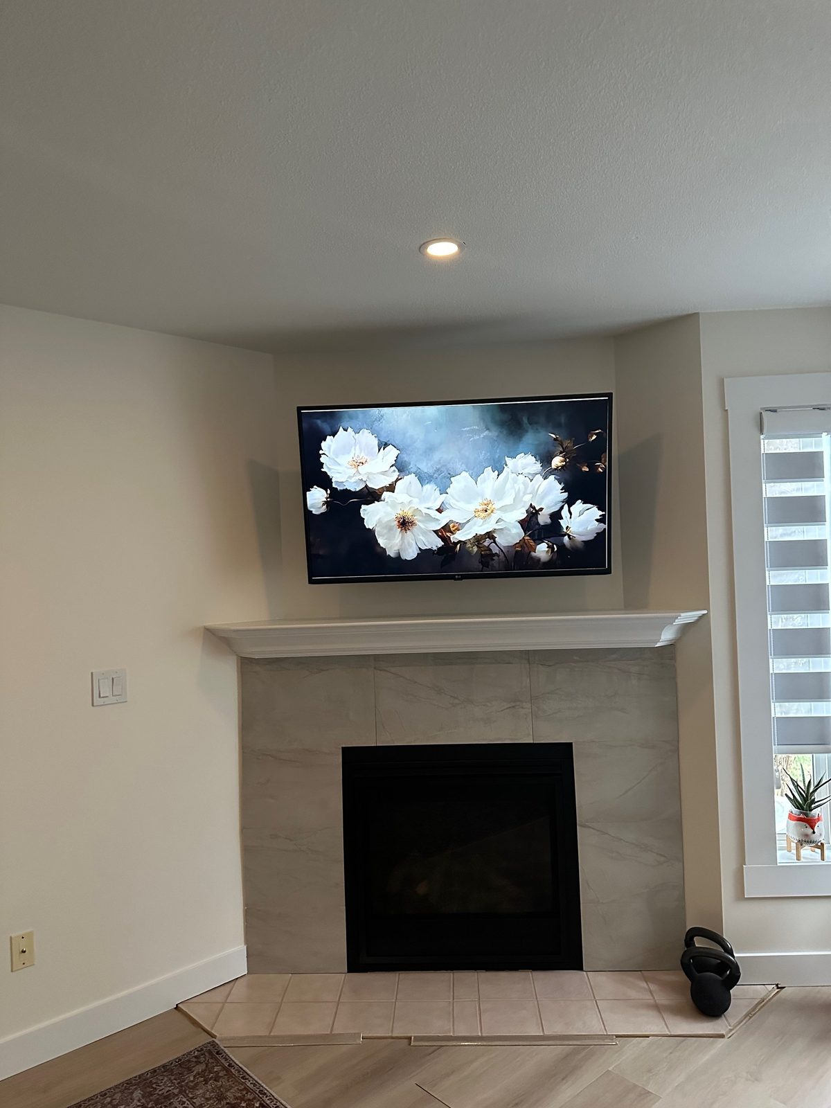 TV wall mounted above a corner fireplace with a porcelain tile surround