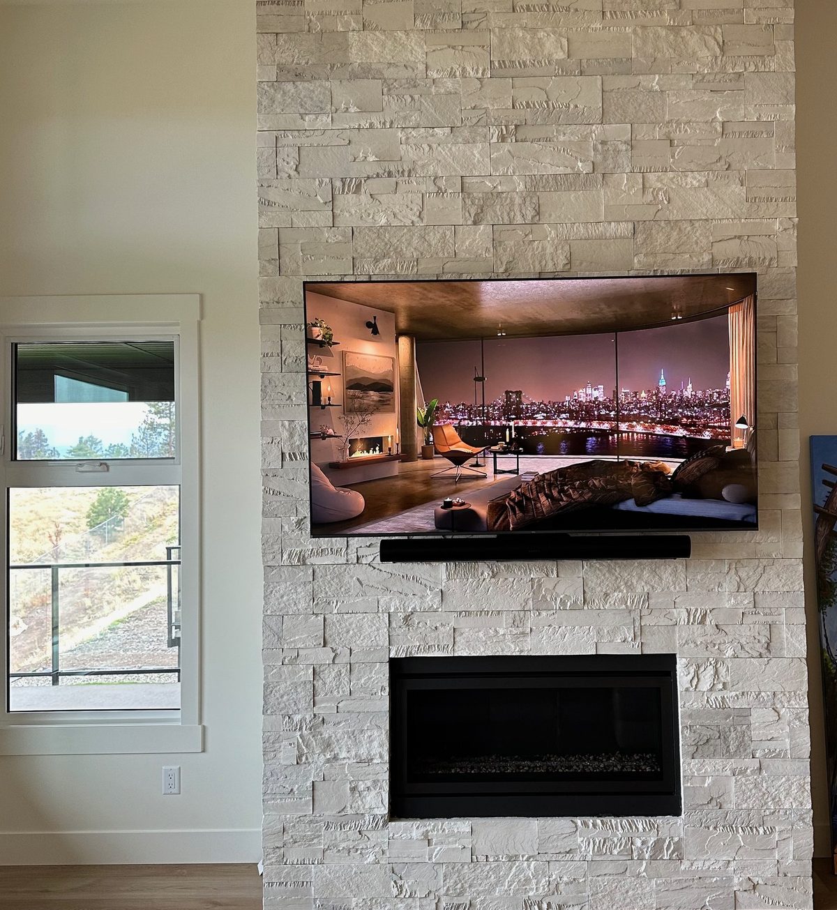 TV and soundbar on a white stacked stone chimney above a linear fireplace