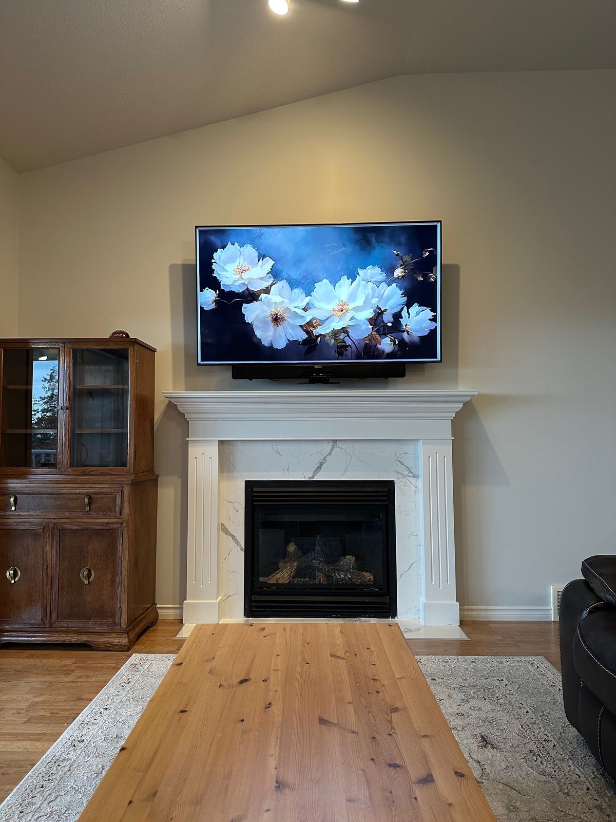 TV above a marble faced fireplace with a soundbar on the mantel