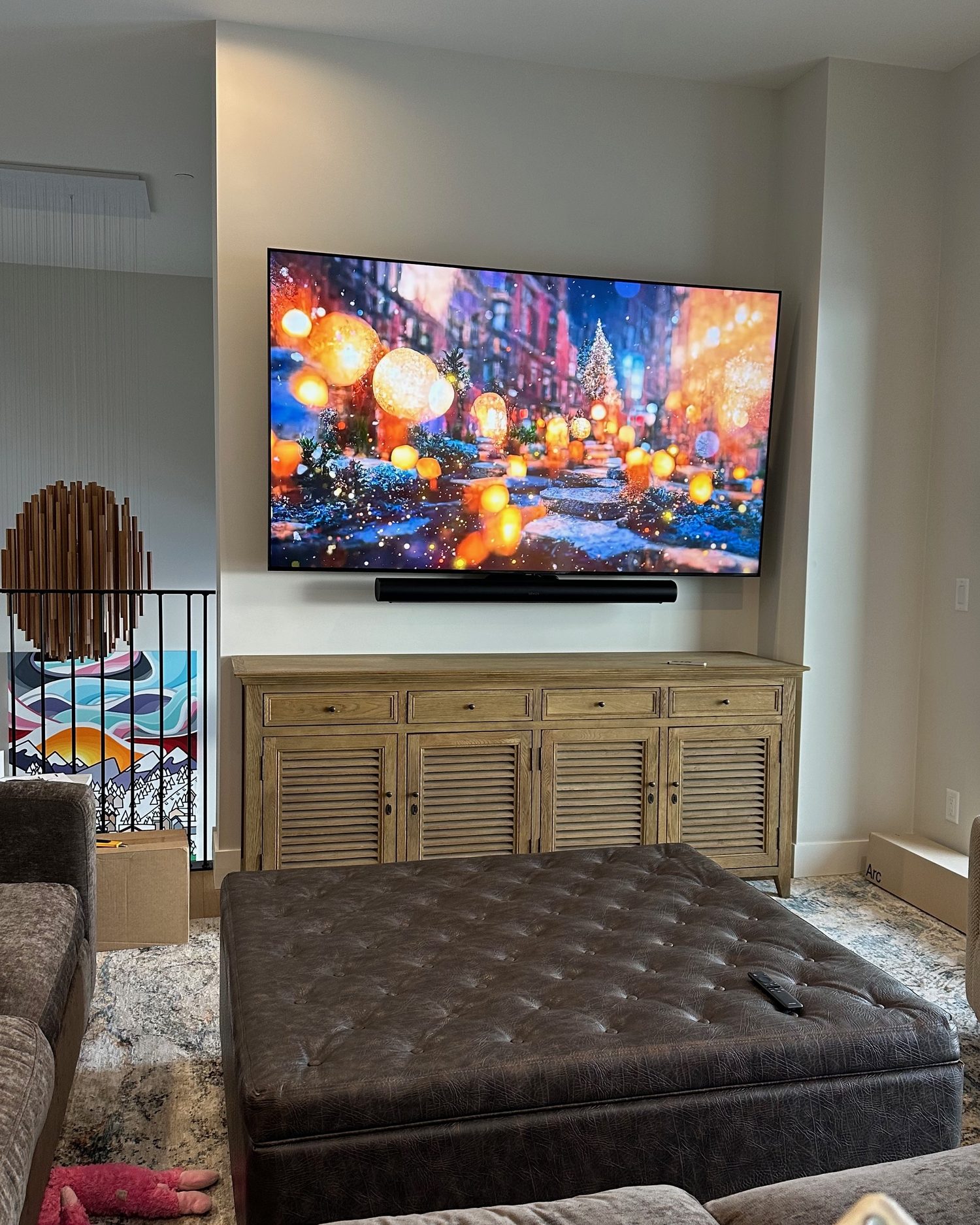 85 inch TV and soundbar mounted in the alcove above a louvered credenza