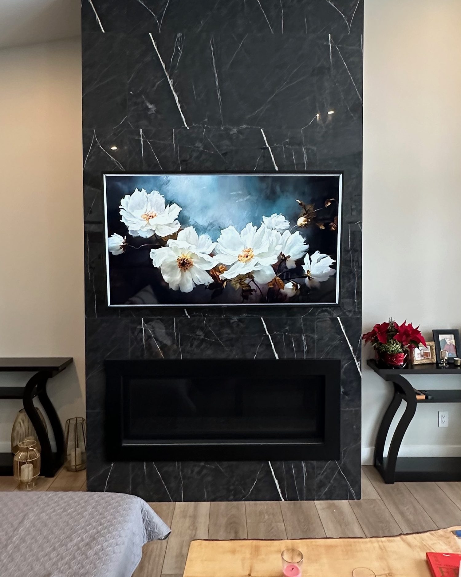 Framed TV mounted on the black marble fireplace wall with no visible cables