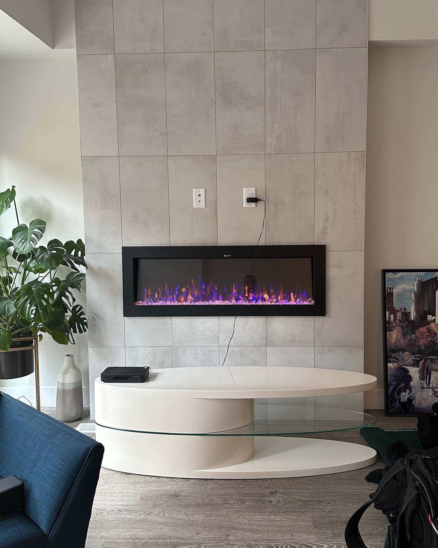 Bare porcelain tile feature wall above a linear fireplace with the outlet still exposed