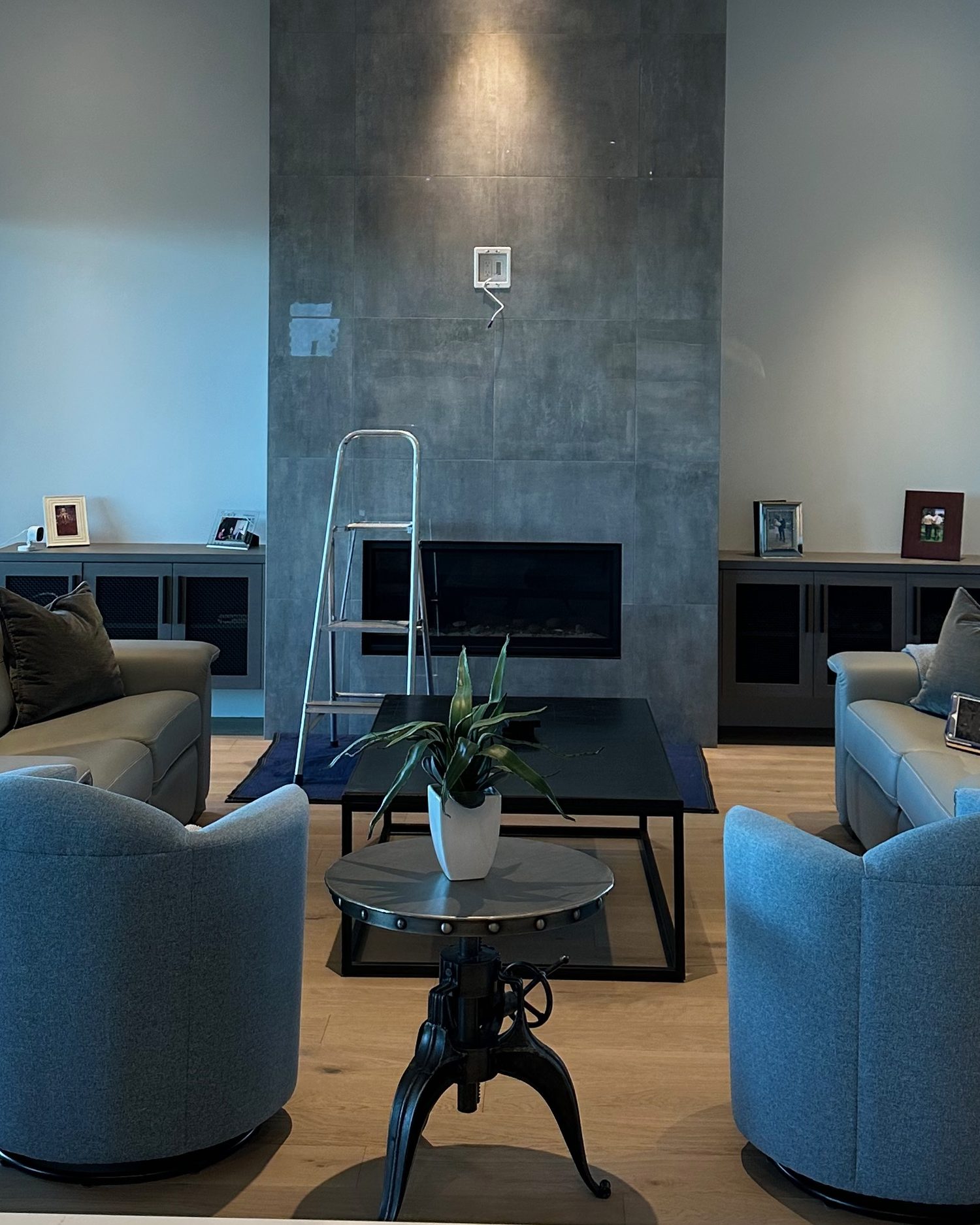 Bare porcelain-tile fireplace wall in a Kelowna living room before the install, with the recessed power and media plate already set