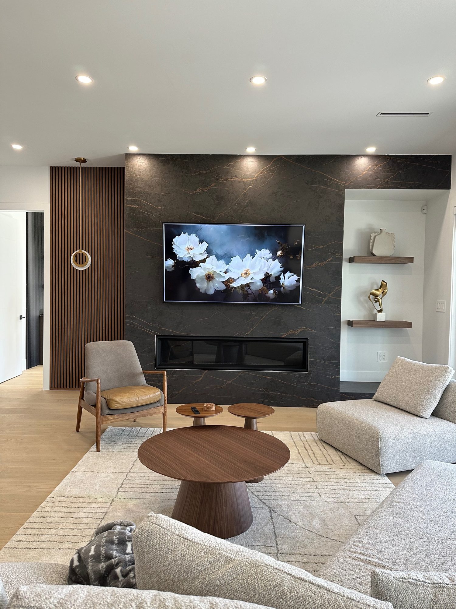TV mounted on a dark veined porcelain feature wall above a linear fireplace in Kelowna